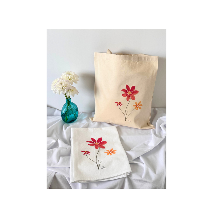 Natural canvas tote bag and matching tea towel featuring the original watercolor painting Better Together displayed with white flowers in a turquoise glass vase.
