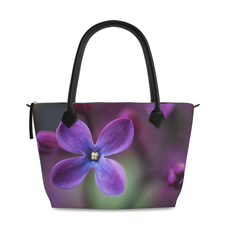 Structured zip top handbag featuring lilac botanical artwork, leather handles, interior pockets, and 17-inch laptop capacity. Canvas Weave