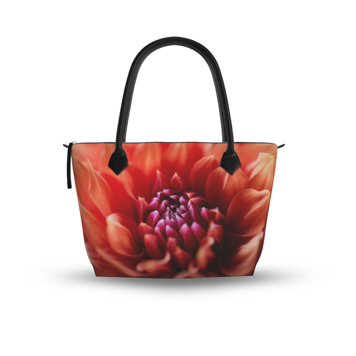 Orange dahlia zip top handbag with warm coral and red petals surrounding a deep magenta center in soft focus, structured silhouette with black leather handles and top zipper closure, botanical art design by Sally Halvorsen Canvas Weave