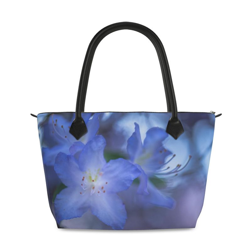 Rhododendron flower zip top handbag featuring a soft bluish purple blossom with layered petals and a gentle green blurred background, structured silhouette with black leather handles and top zipper closure, botanical art design by Sally Halvorsen in Canvas Weave
