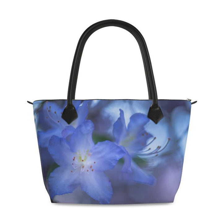 Rhododendron flower zip top handbag featuring a soft bluish purple blossom with layered petals and a gentle green blurred background, structured silhouette with black leather handles and top zipper closure, botanical art design by Sally Halvorsen in Canvas Weave
