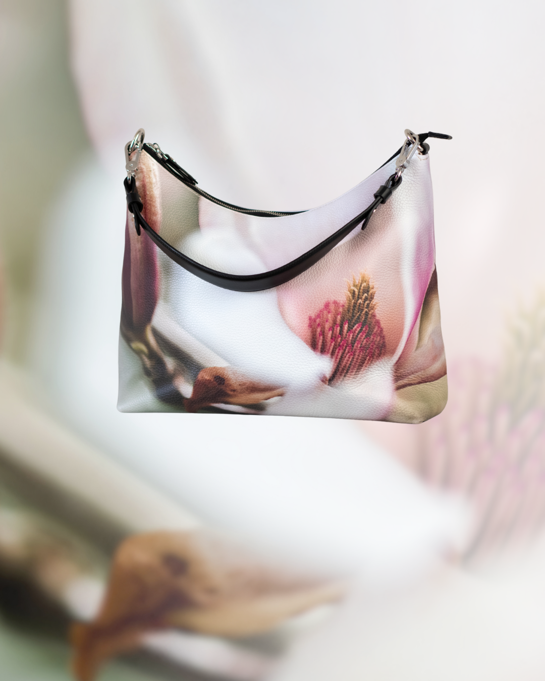 Handbag printed with a large white flower with blush pink details, shown against a soft neutral background.