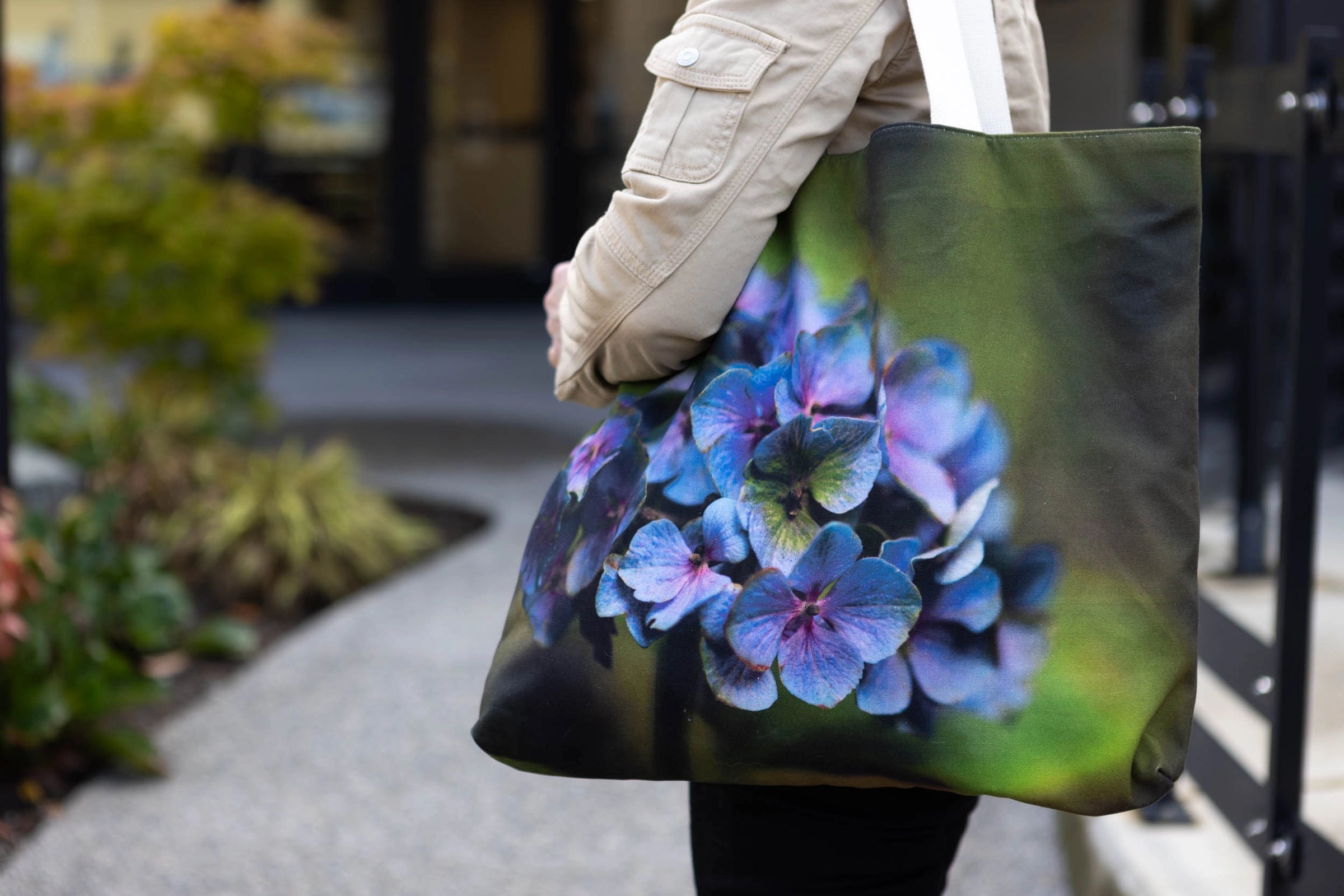 Person wearing a tote bag on her shoulder with a floral design outdoors
