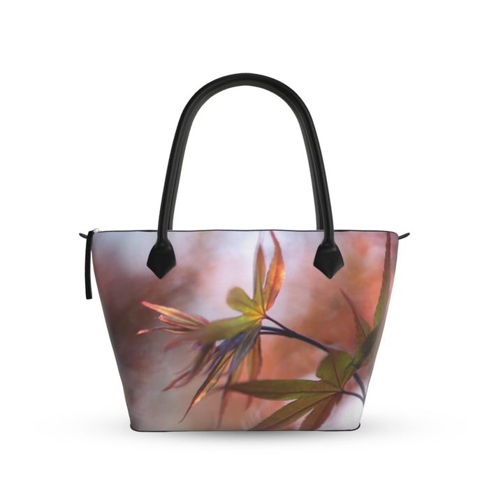 Maple leaf zip top handbag with warm autumn tones of red, orange, and green leaves in soft focus, structured silhouette with black leather handles and top zipper closure, nature inspired design by Sally Halvorsen-Smooth Nappa