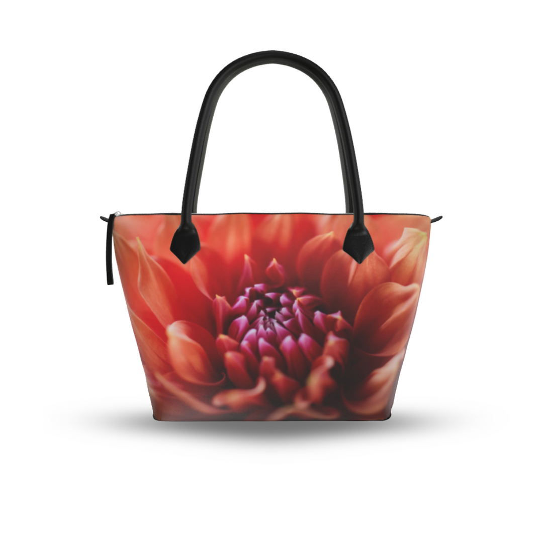 Orange dahlia zip top handbag with warm coral and red petals surrounding a deep magenta center in soft focus, structured silhouette with black leather handles and top zipper closure, botanical art design by Sally Halvorsen. Smooth Leather