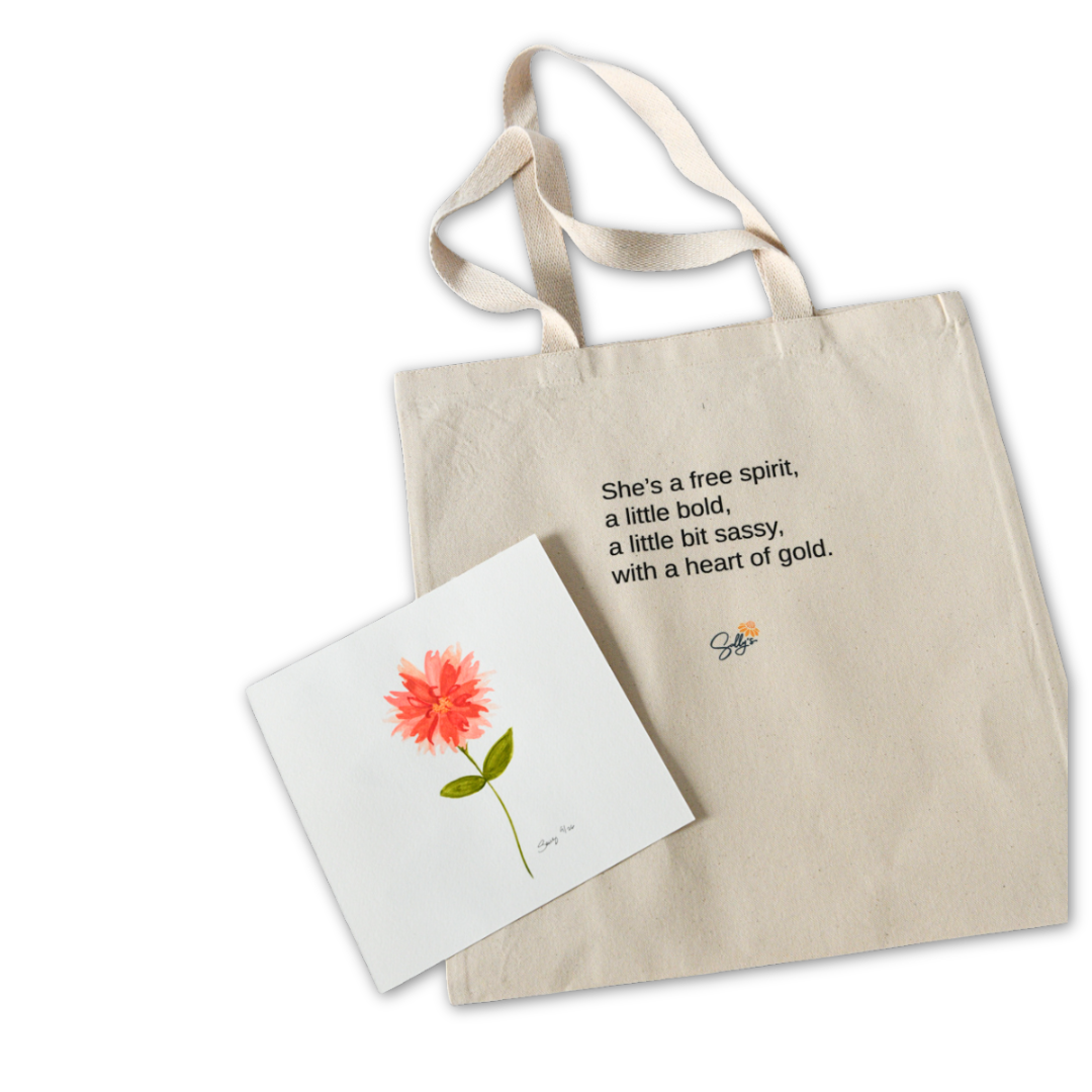 Back of A Little Bit Sassy canvas tote beside a matching coral flower card. Text reads, “She’s a free spirit, a little bold, a little bit sassy, with a heart of gold.”