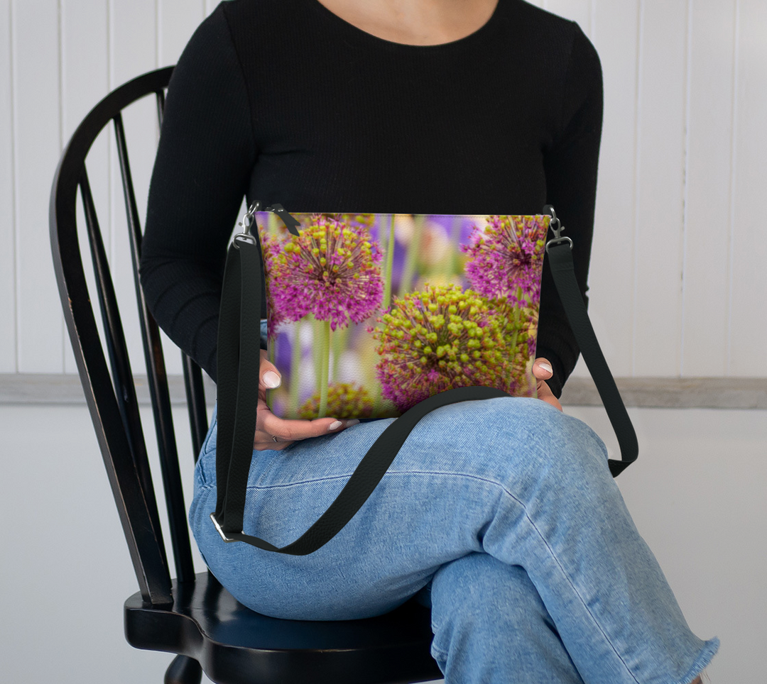Allium Faux Leather Crossbody Purse by Allium — compact vegan bag with purple floral print and black strap displayed on models lap.